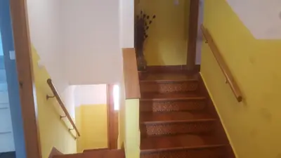 a staircase in a house with wooden floors and yellow walls at Pensión Boavista in Portomarin