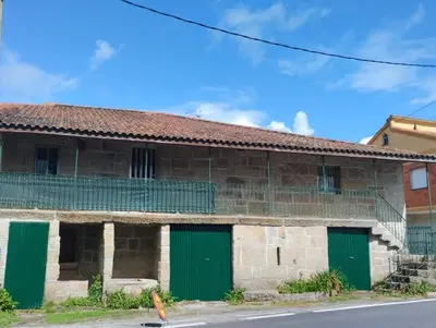 an old brick building with green doors on a street at Casa Fuentefria in Ourense