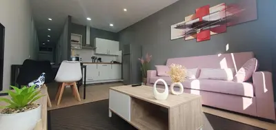 a living room with a purple couch and a kitchen at Pisos uso turistico Torno-Cubelas-Caosa Buenavista in San Ciprián