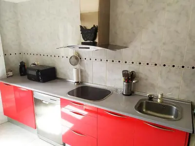 a kitchen with red cabinets and a sink at Piso BOLBORETEIRO in Allariz