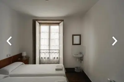 a bedroom with a bed and a window with two arrows at Casa Anglicana del Peregrino/ Pensión Santa Cristina in Santiago de Compostela