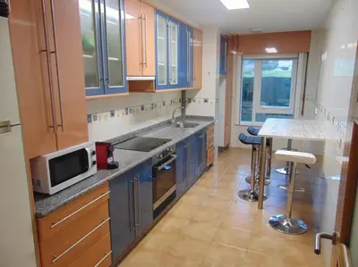 a kitchen with blue cabinets and a sink and a microwave at apartamento con jardin in Santiago de Compostela