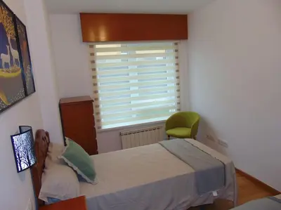 a bedroom with a bed and a green chair at apartamento con jardin in Santiago de Compostela