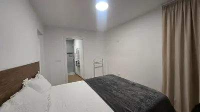 a bedroom with a white bed with a gray blanket at C&C Suite in San Ciprián