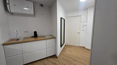 a kitchen with white cabinets and a sink and a hallway at C&C Suite in San Ciprián