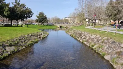 a river with a bridge in a park at Mirador del castillo in Monforte de Lemos