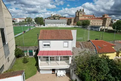 a white house with a red roof and a field at Mirador del castillo in Monforte de Lemos