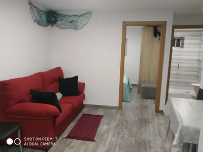 a living room with a red couch and a mirror at O RECUNCHO DE BERE in Ribadeo