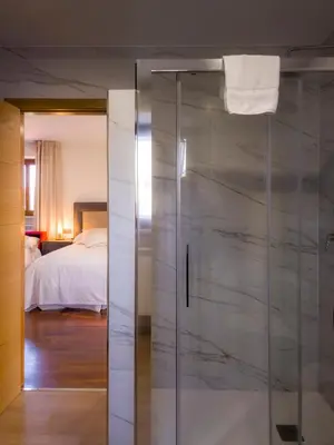 a glass shower door in a room with a bed at Casa Rural Camino Real Completa in Melide