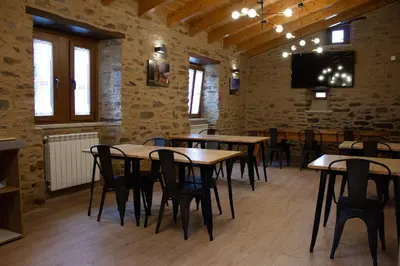 a dining room with tables and chairs and a flat screen tv at Casa Rural Camino Real Completa in Melide