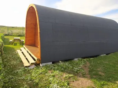 a large black building with a bench in a field at Bungalow 3 personas - Camping Playa de Tapia in Tapia de Casariego