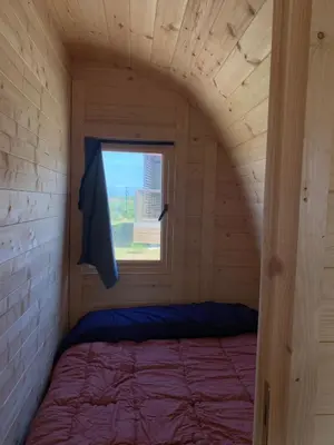 a bed in a wooden room with a window at Bungalow 3 personas - Camping Playa de Tapia in Tapia de Casariego