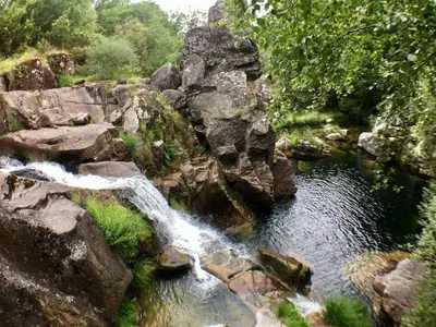 a waterfall on the side of a river with rocks at Casa Rural Turística Casa Nicolau 1 in Barbudo